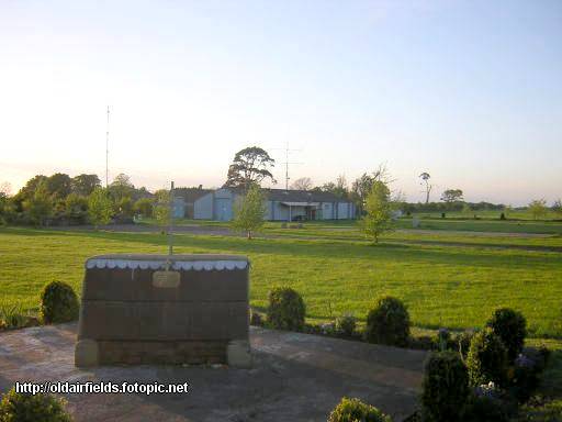 View of the RAF Sandtoft memorial with airfield buildings in the background.